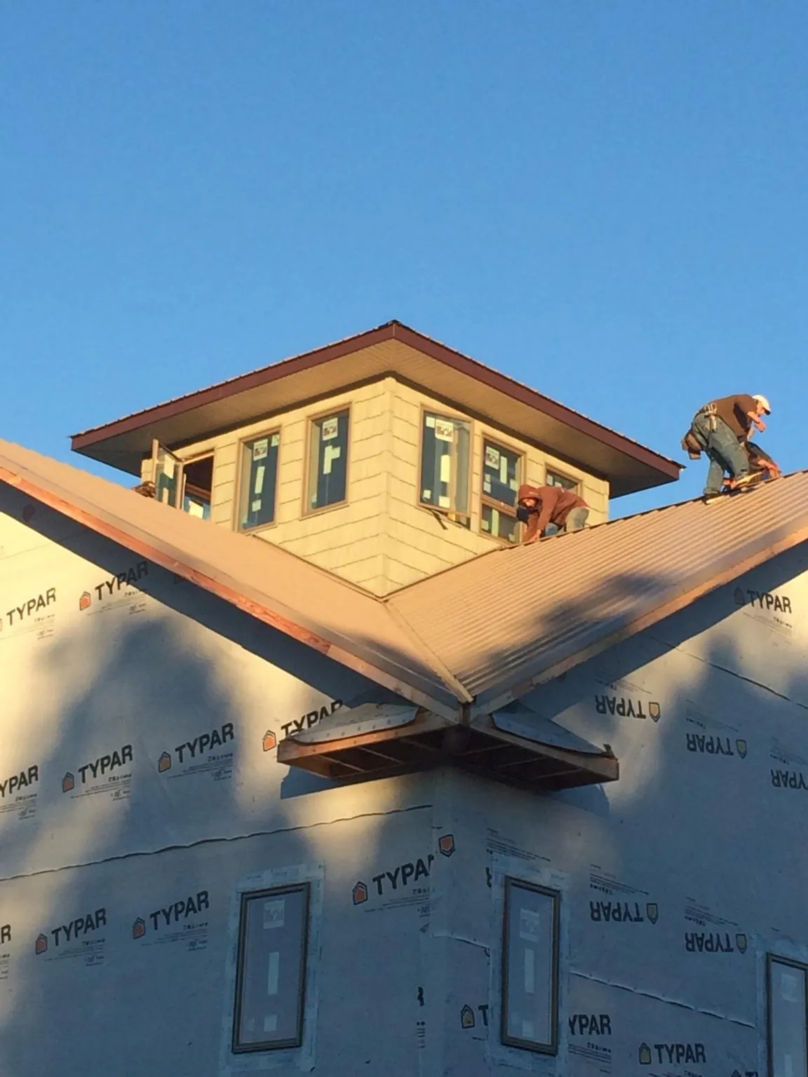 Roofers working around a rooftop cupola on a new metal roof at sunset — Roof Waterproofing in Lebanon by Roofing Brothers